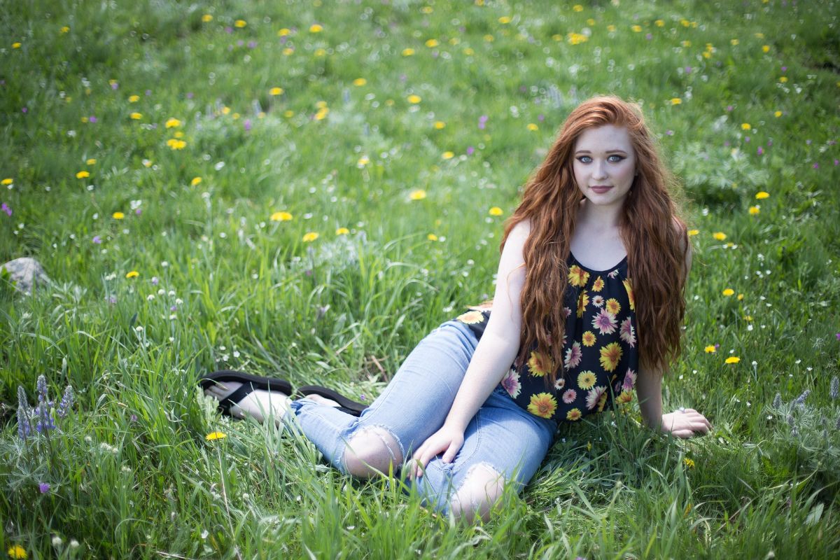 No Mow May - Woman lounges on long grass with flowers