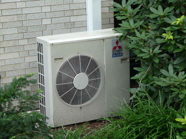 AC Unit by house near shrubs