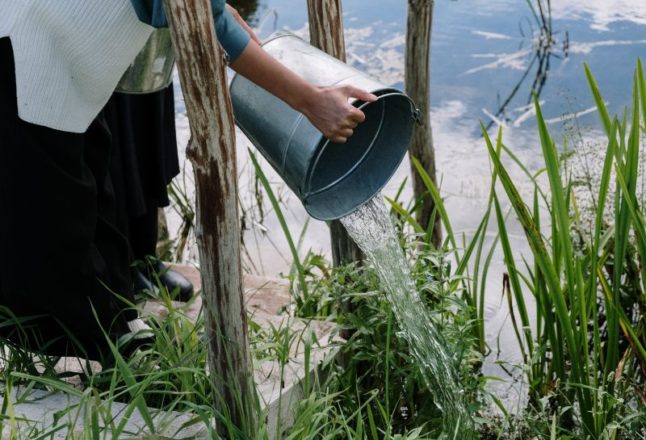 Woman empties bucket of water