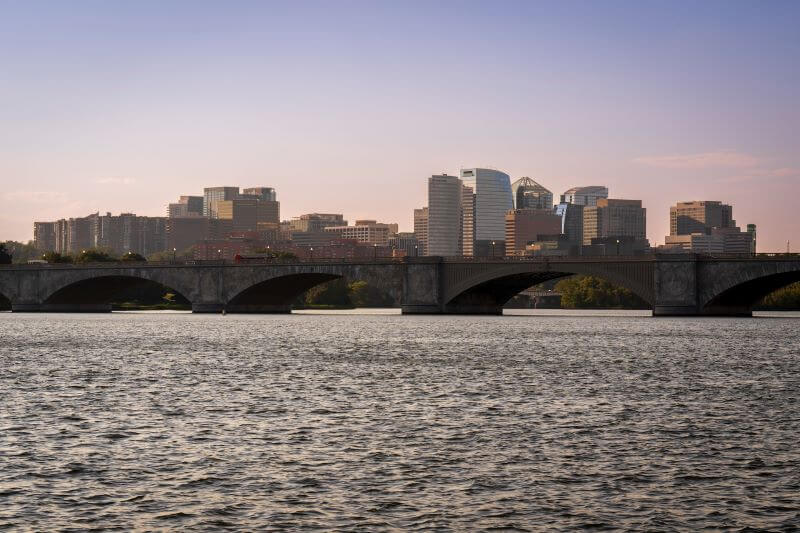 A view of the Arlington, Virginia, skyline shot from Washington, DC, with a view of a bridge and the Potomac River in the foreground