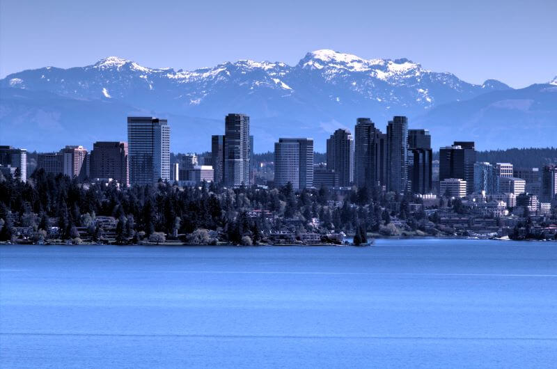 Snowy mountains tower over Bellevue, a city of high-rises overlooking the water.