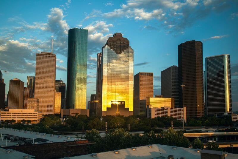 The sunset reflects on high-rise buildings in Houston.