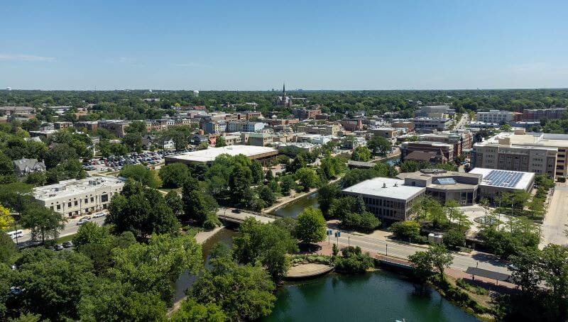 A green-blue river runs through the downtown neighborhood of Naperville.