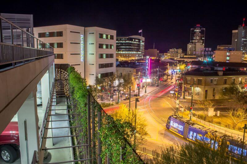 Downtown Tucson in the evening, shot from a balcony, with views of buildings and a light rail train