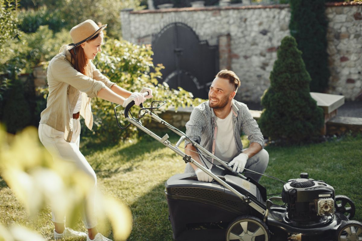 Happy woman mows lawn with man sitting beside her
