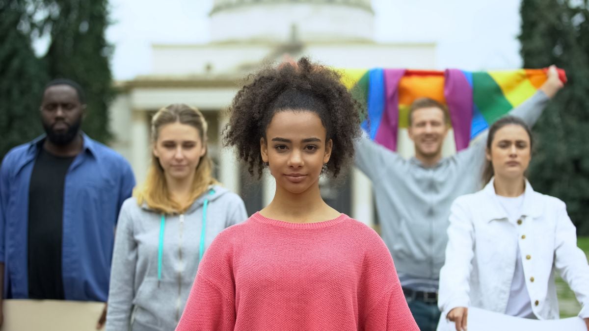 A diverse group of people - one person holds a pride flag