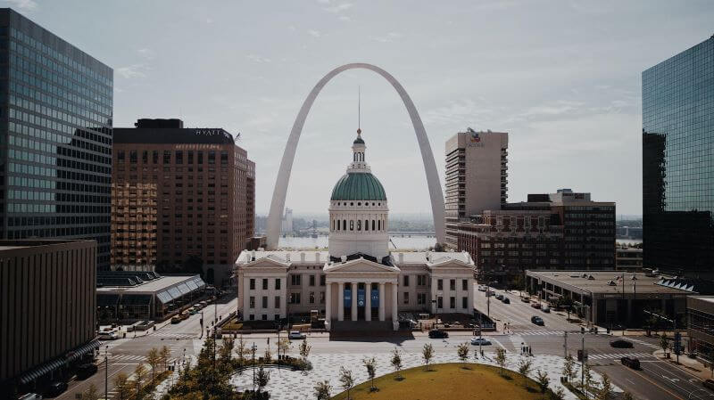 The Gateway Arch towers behind the Old Court House — a stately white building with a teal dome — in St. Louis