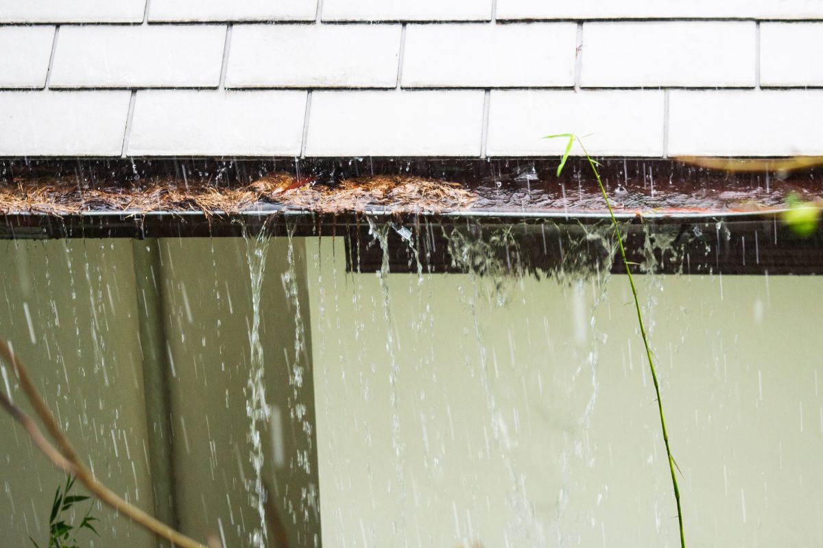 Text: Leaky Gutters | Background Image: Gutter Water Overflow from Gutter