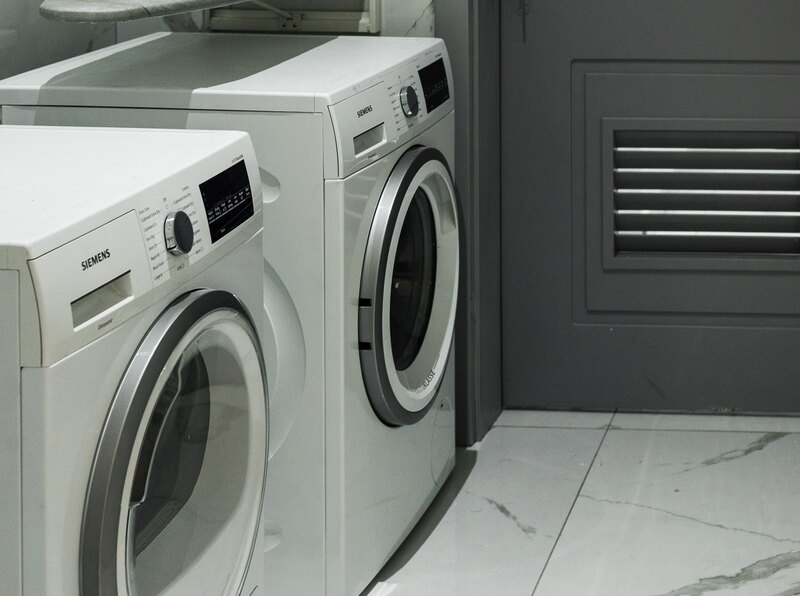 Interior pictures of a Stylish modern Washing Machine in a laundry area.