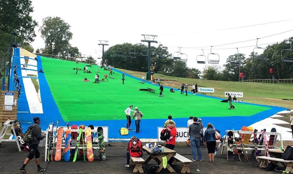 Grass ski slope at Buck Hill in Minnesota with skiers on the slope and snowboards in the foreground