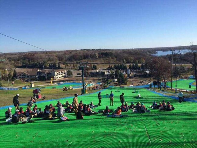 Buck Hill grass ski slope in Minnesota with skiers atop the slope waiting to go down the grassy hill