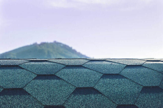 Designer hexagonal asphalt shingles on a roof with a mountain in the background