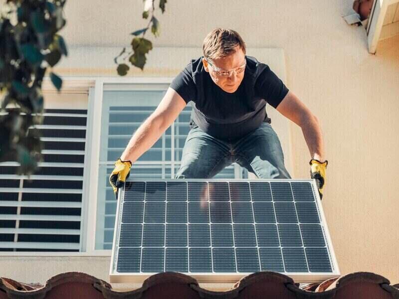 man installing solar panel on his roof