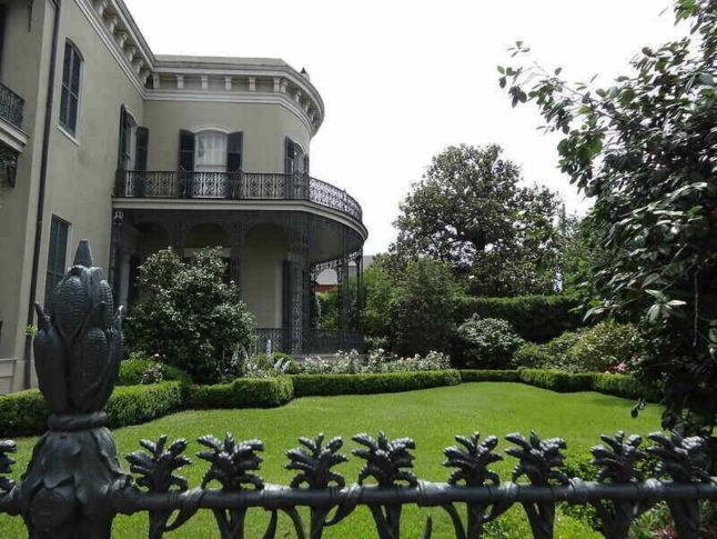 A wrought iron fence outside a stately New Orleans home
