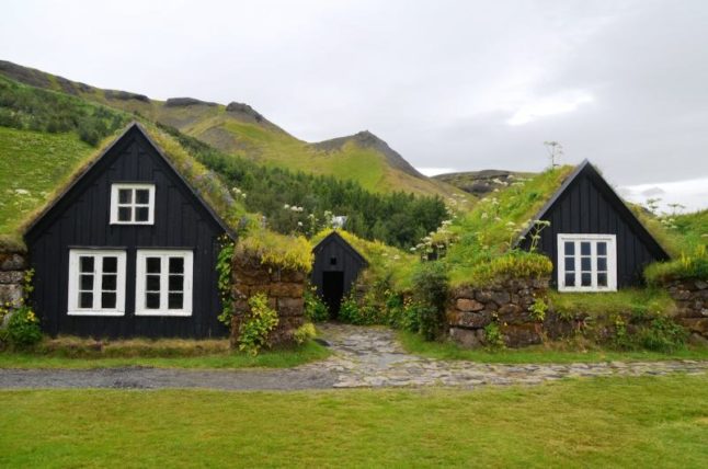 Two wooden houses on green landscape with green roofs