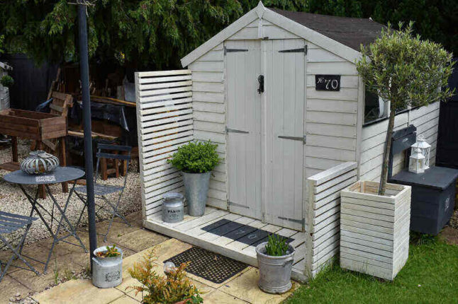 White seemingly prefab she shed with porch and patio