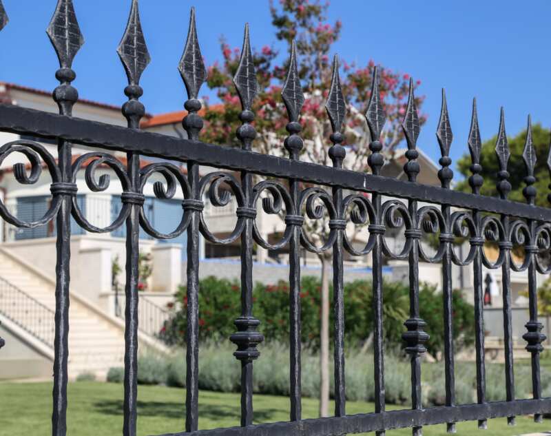 A metal fence of a beautiful lawn