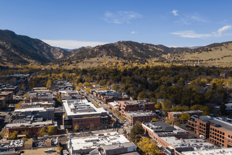 An aerial view of Boulder, Colorado, with green mountains surrounding the city