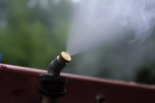 Nebulizer or atomiser produce mist in the garden with green tree background.