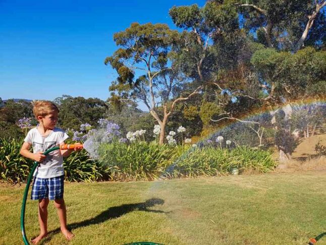 Boy making a rainbow with a garden hose