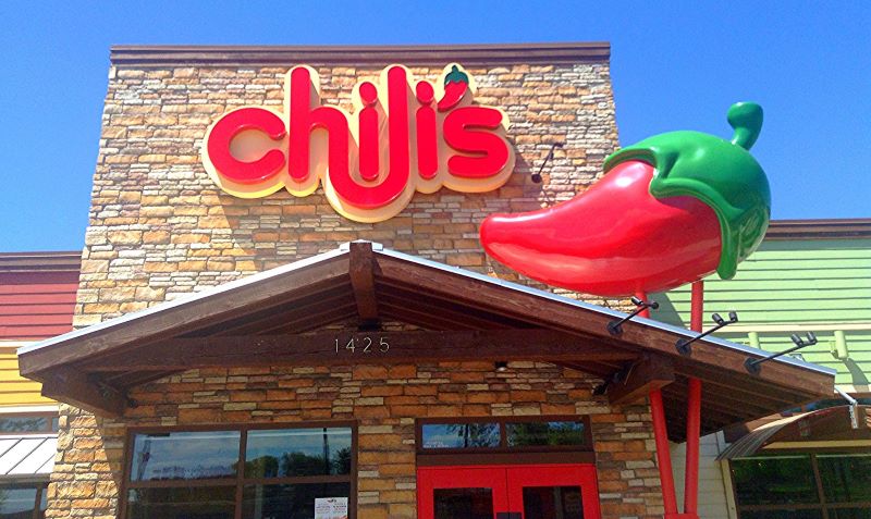 The entrance to a Chili’s location, with a large 3-D red chili pepper next to the establishment’s sign. 