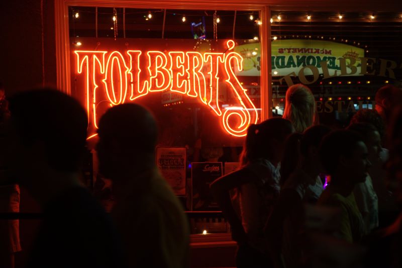 A neon sign reading “Tolbert’s” glows behind a crowd of hungry folks.