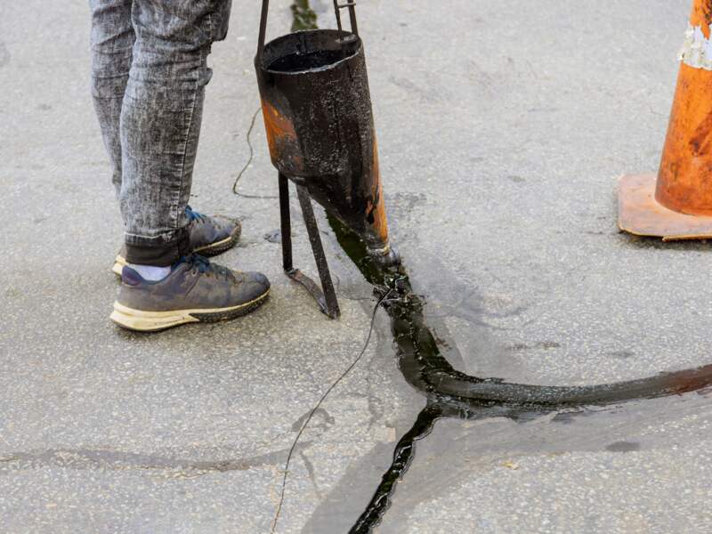 A man sealing asphalt driveway