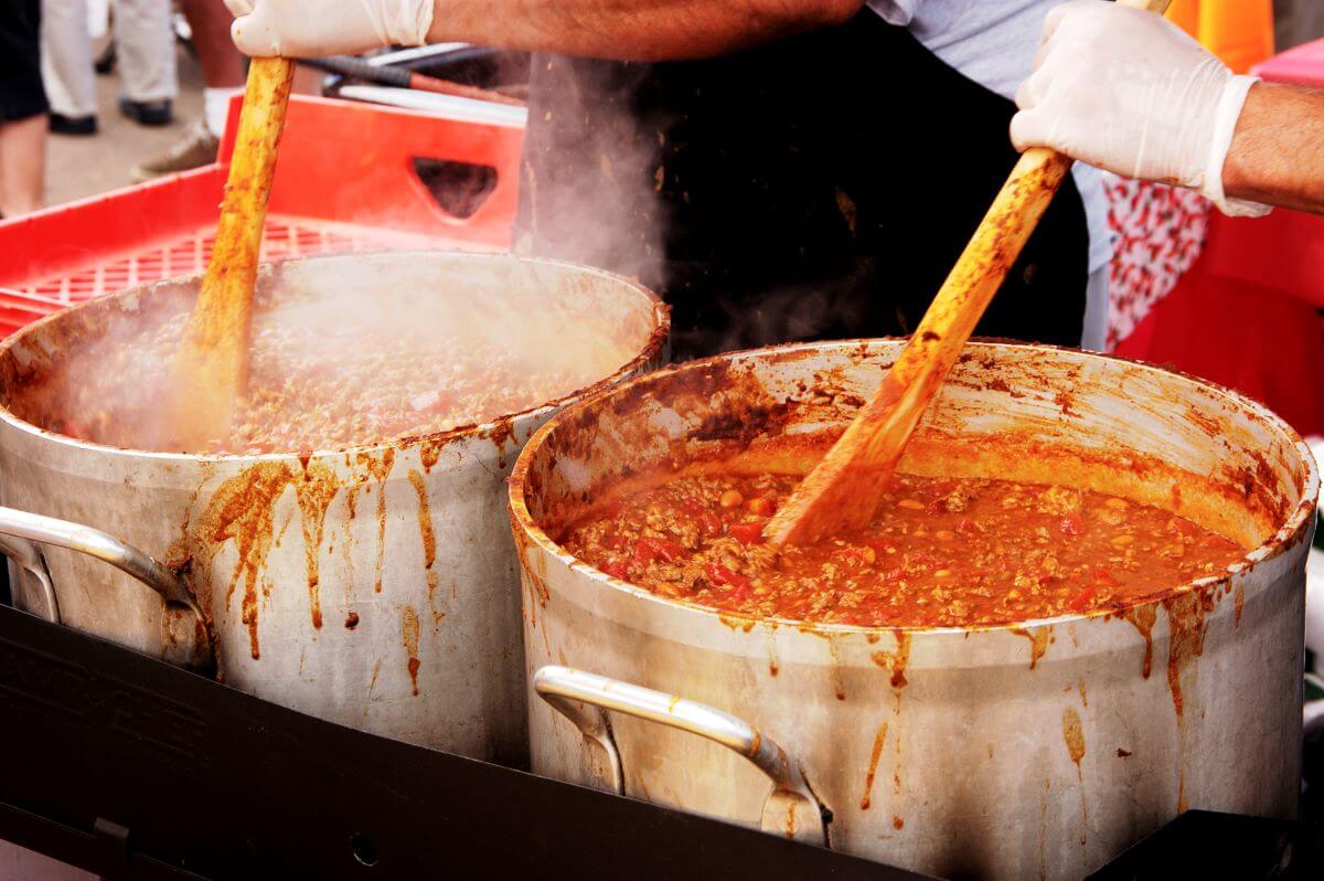 Chili cookoff competitors stir two large pots of chili