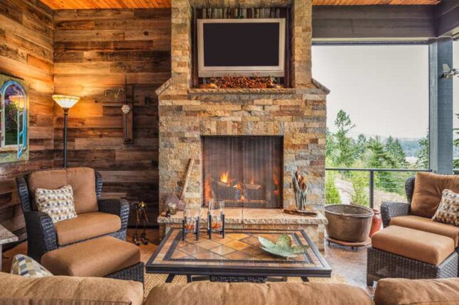 Covered Outdoor Patio Outside New Home with Couch, Chairs, TV, Fireplace, and Roaring Fire