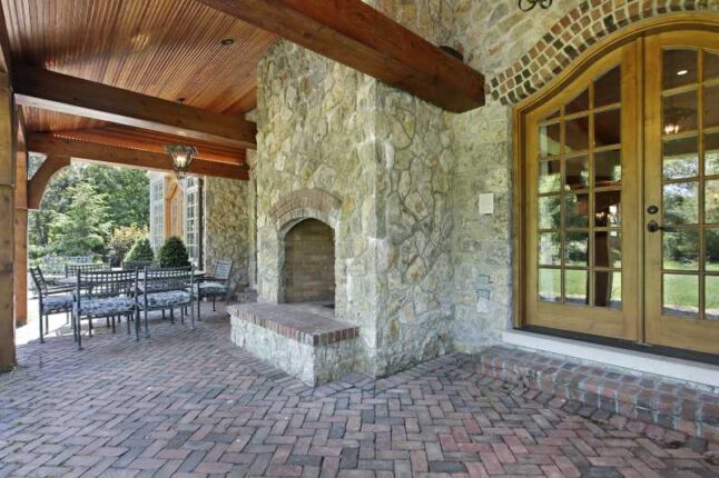 Brick patio outside luxury home with stone fireplace