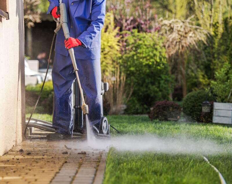 A man doing power washing of concrete pathway