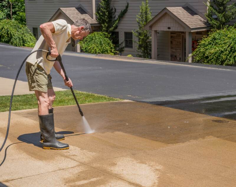 A man doing power washing of concrete driveway