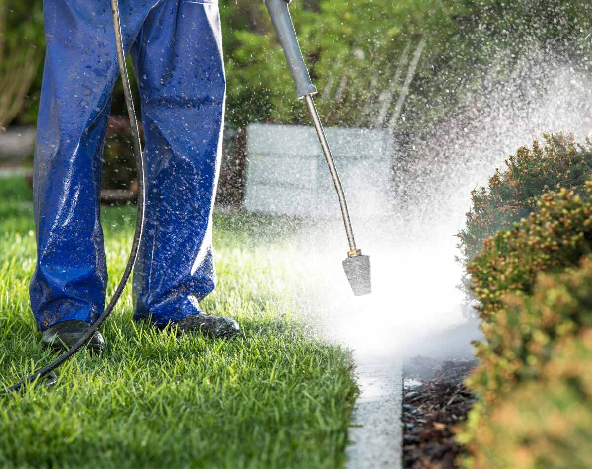 A person doing power washing of his garden