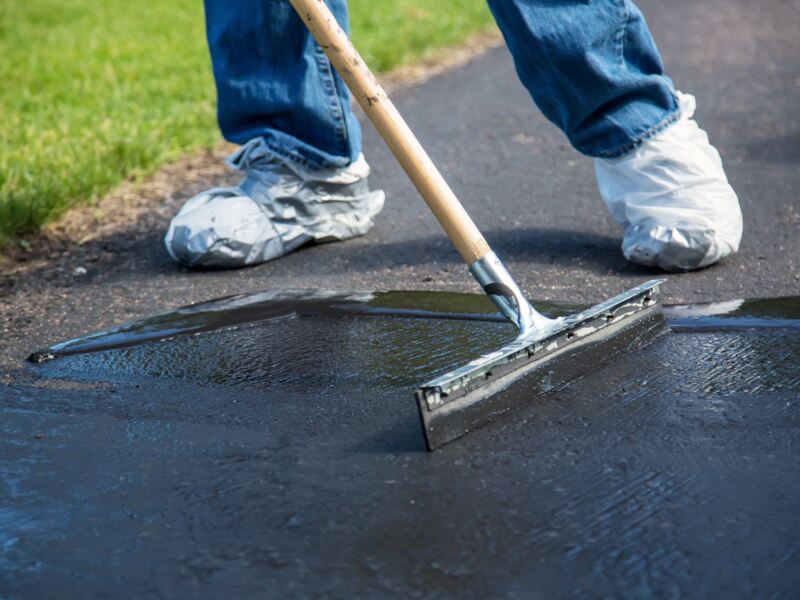 A person sealing a driveway with coating