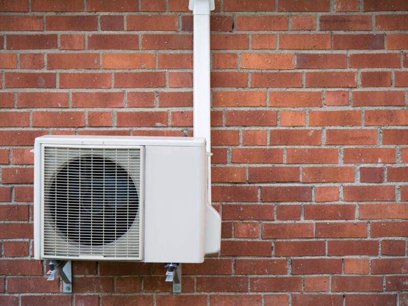 A heat pump installed with red brick in the background