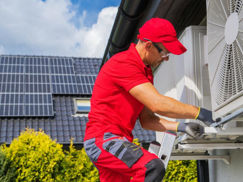 An HVAC Worker performing maintenance of heat pump