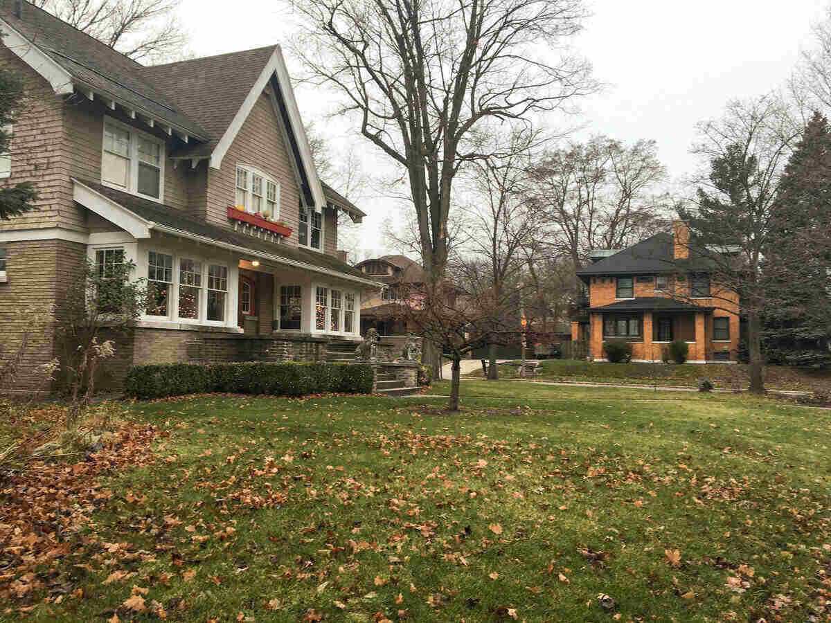 Photo of the lawns of two homes in Grand Rapids, Michigan. Lawns have leaves on top and the homes are stately.