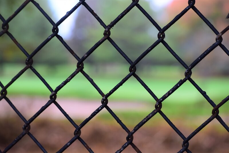 A black chain link fence with green background