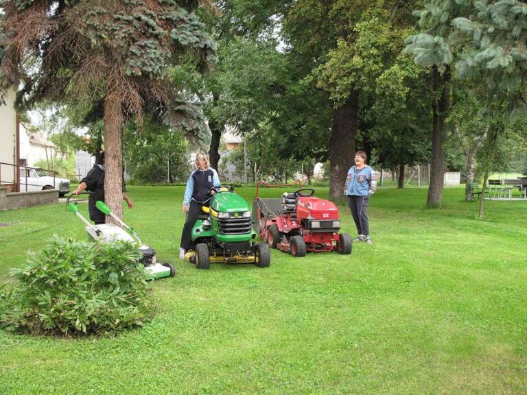Three women on a lawn with their lawn mowers
