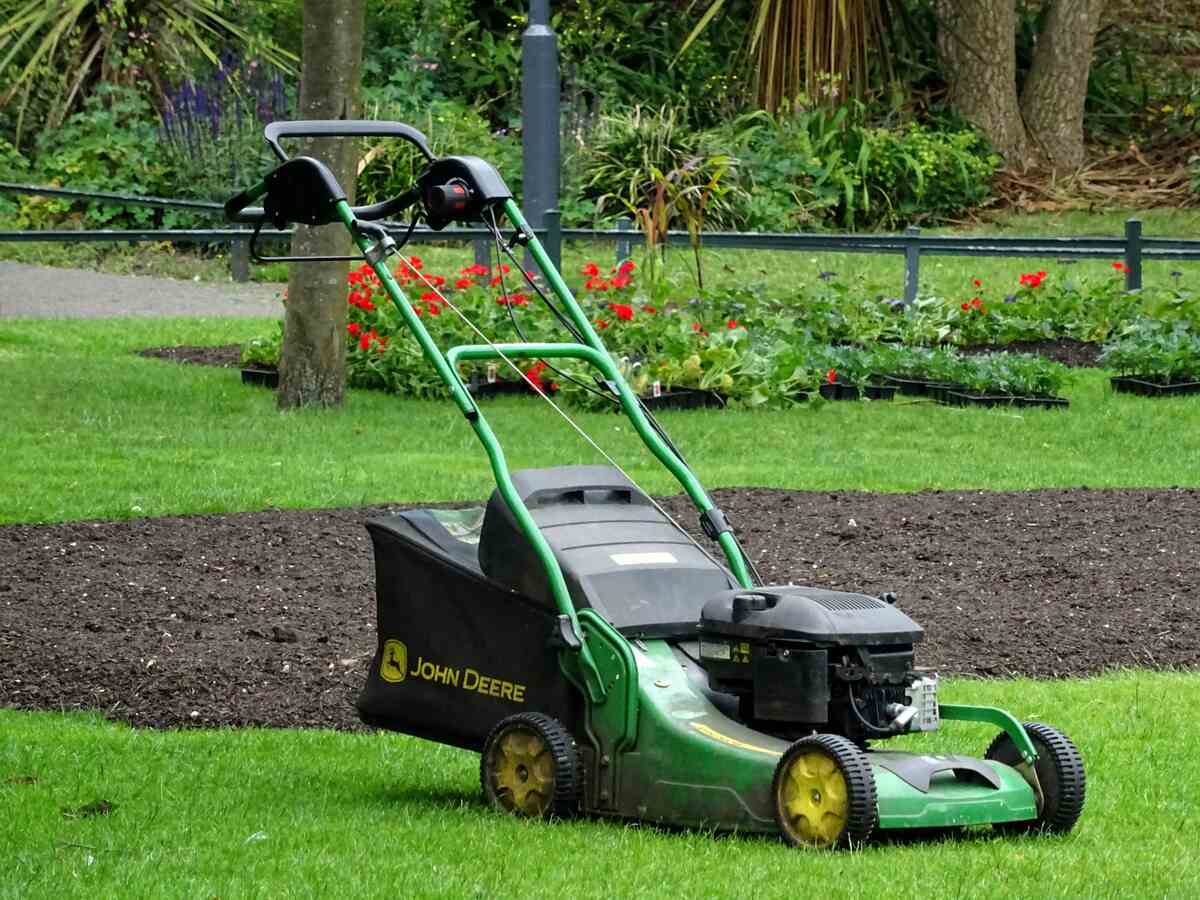 A green lawn mower in a grassy lawn