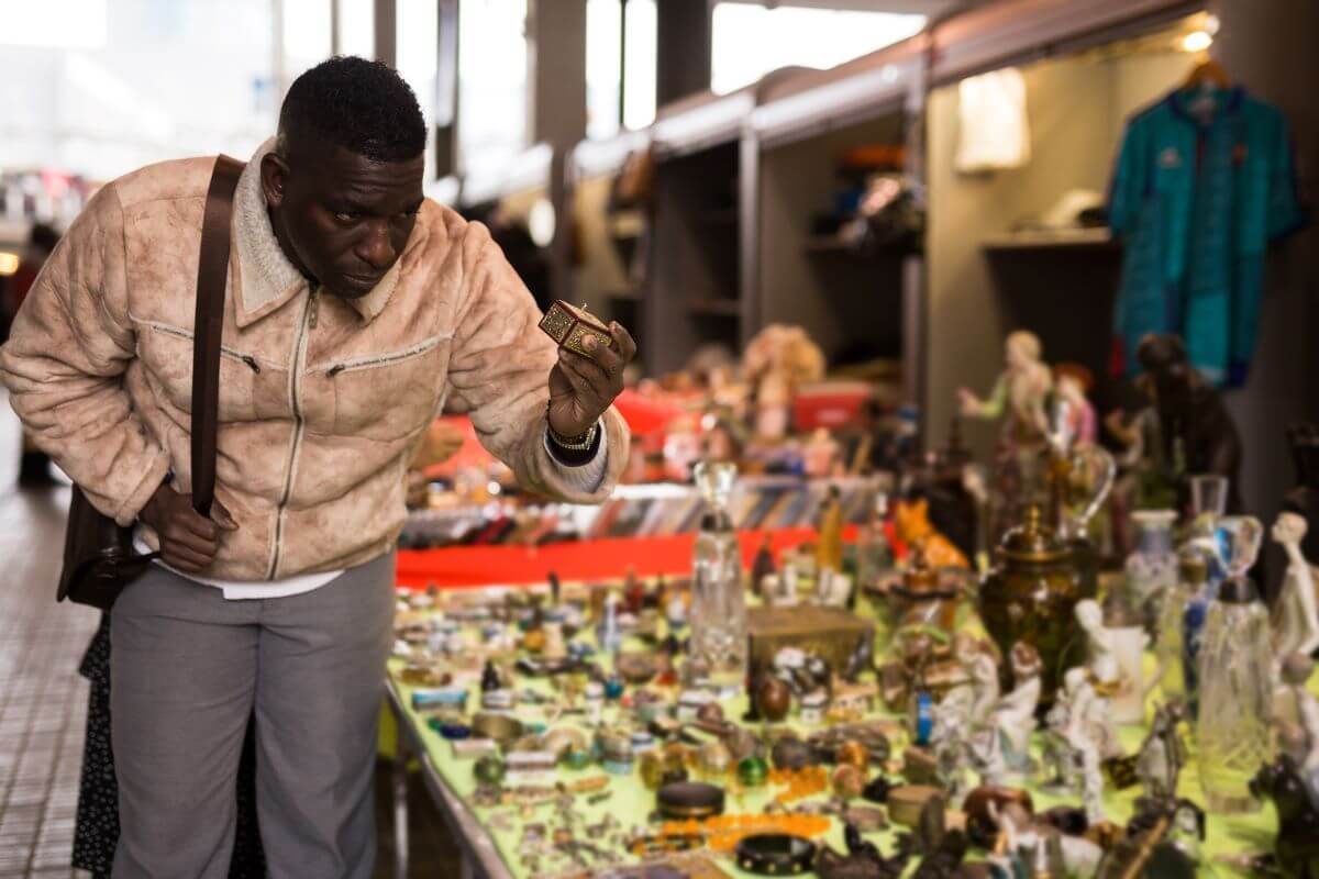 A man examines an antique ornamental box at a flea market.