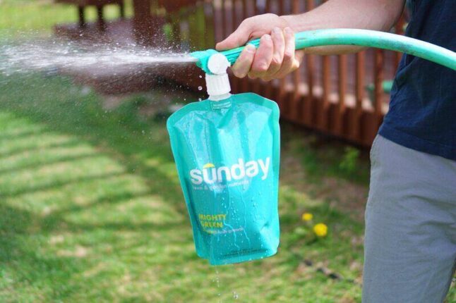 Sunday lawn care treatment pouch attached to a garden hose