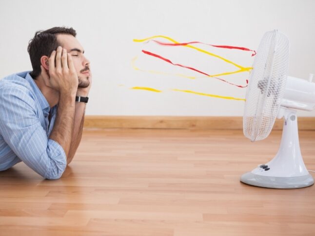 man lying in front of a fan