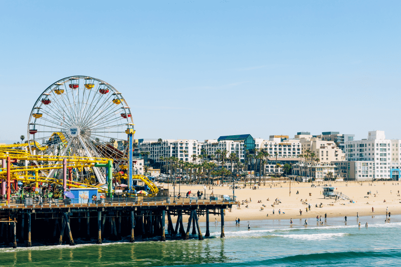 People crowd the beach and pier in sunny Santa Monica, California