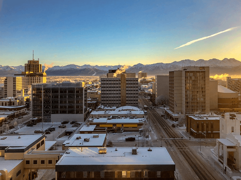 A mountain range surrounds the high-rise buildings in Anchorage on a chilly winter day.
