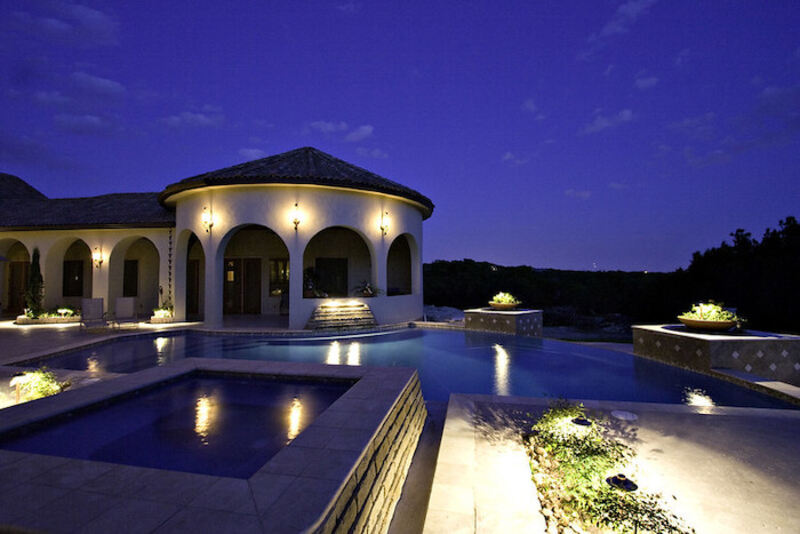 Dark blue pool lit up by lights against dark blue sky