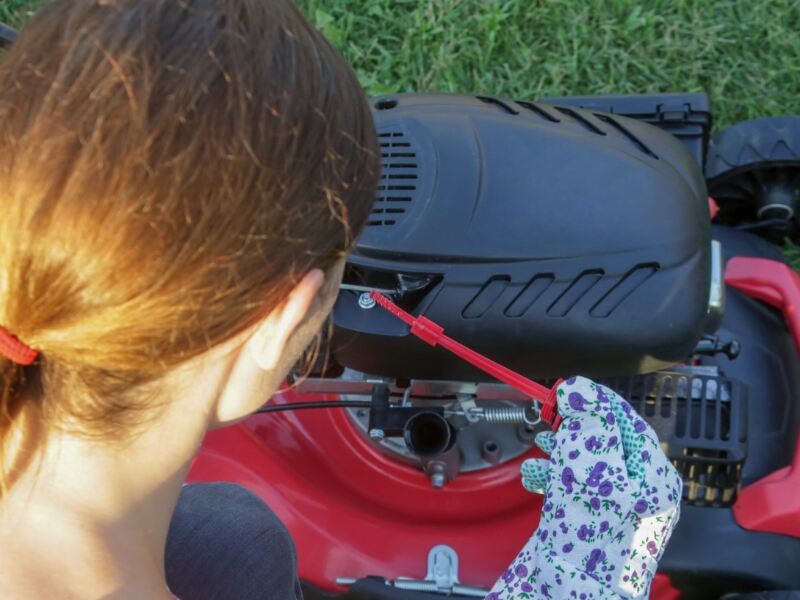 woman checking oil in lawn mower