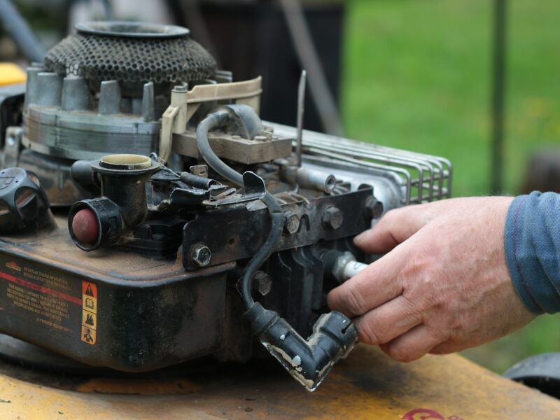 man changing a spark plug on a lawn mower