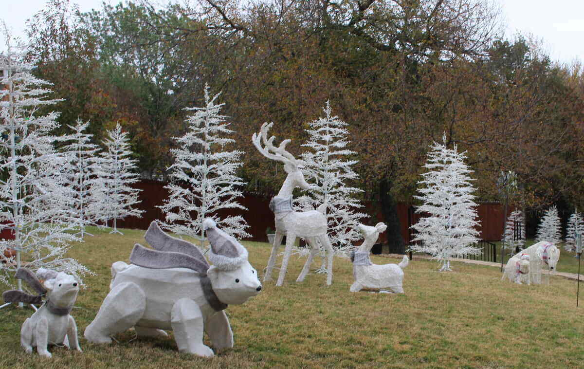 Holiday decorations on the lawn - white deer, bears, and bare Christmas trees