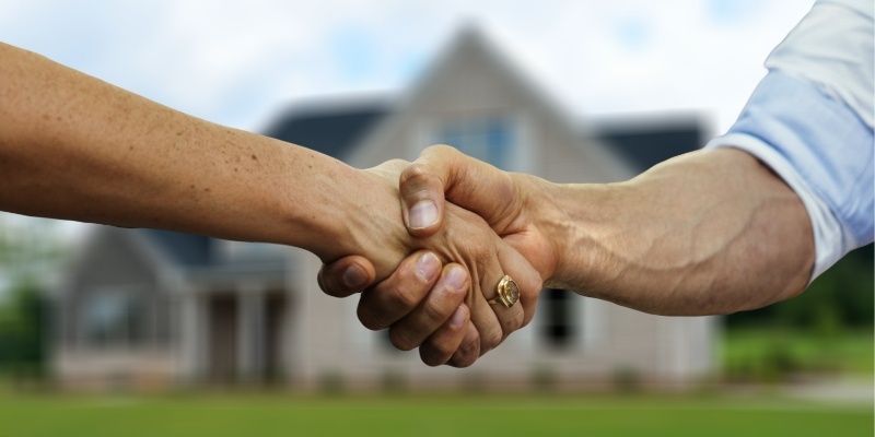 shaking hands in front of a house